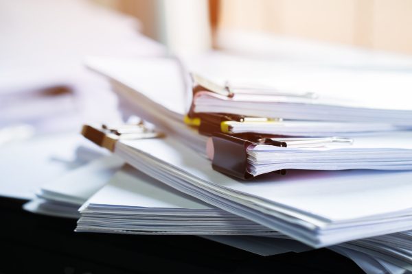 Stack of papers documents in archives files with clip papers on table at offices,  Busy offices and Pile of data unfinished folders on office desk indoor near window,  Business concept.